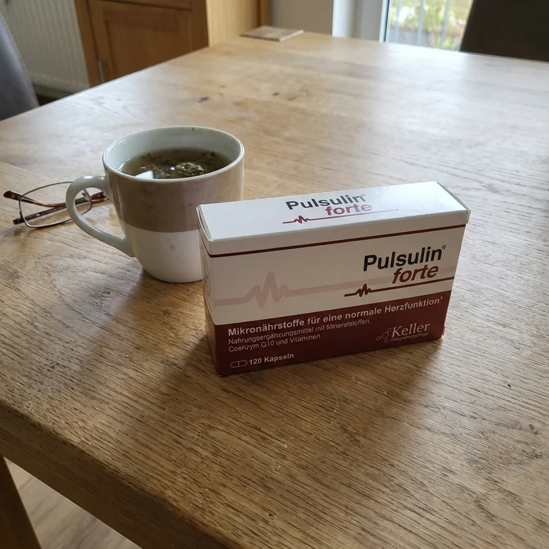 Pulsulin Verpackung auf einem Holztisch neben einem Glas Wasser