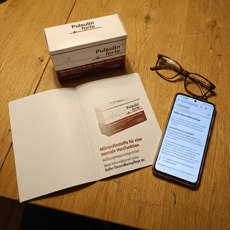 Broschüre aufgeschlagen mit Pulsulin-Produktfoto, daneben Smartphone mit Website und Lesebrille